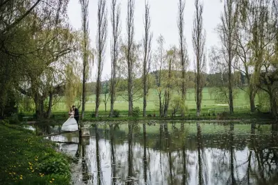 a bride and groom standing in front of a pond at Dvůr Pecínov in Benešov