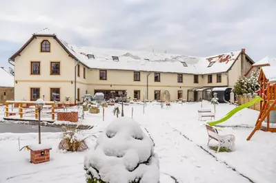 a large building with snow on the ground at Kokořín Apartments in Kokořín