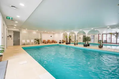 a large swimming pool in a hotel lobby with a large blue pool at Kokořín Apartments in Kokořín