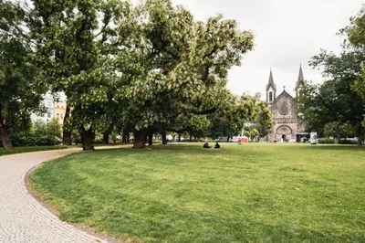 a park with trees and a church in the background at K-14 Apartment in Prague