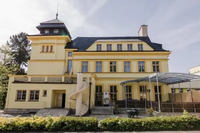 a large yellow building with a clock tower on top at Palace Inn in Jíloviště