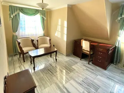 a living room with a table and chairs and a desk at Palace Inn in Jíloviště