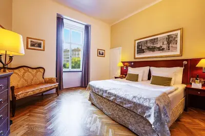 a bedroom with a bed and a chair and a window at Wenceslas Square Hotel - Czech Leading Hotels in Prague