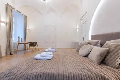 a living room with a large bed with blue pillows at Arch IV. in Prague