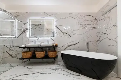 a bathroom with a black tub and a marble wall at Arch IV. in Prague