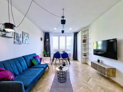 a living room with a blue couch and a tv at Jana's WoW apt, 2BR, Metro next door, near the airport in Prague