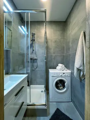 a bathroom with a washing machine and a shower at Jana's WoW apt, 2BR, Metro next door, near the airport in Prague