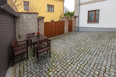 a patio with two benches and a table and a house at Penzion Apartmány Resident in Poděbrady