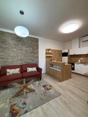 a living room with a red couch and a kitchen at Penzion Apartmány Resident in Poděbrady