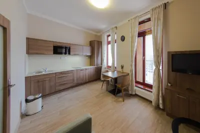 a room with a kitchen with a table and a television at Penzion Apartmány Resident in Poděbrady