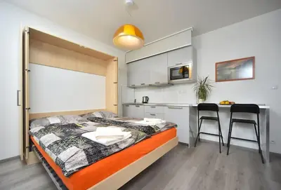 a bedroom with a bed and a kitchen with a table at Appartment Waltrovka, free parking in Prague