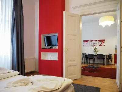 a bedroom with a red wall with a tv on it at Havelska Old Town Residence in Prague