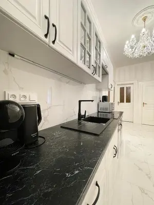 a kitchen with a black counter top and white cabinets at Stupartska - Premium Old Town Residence in Prague