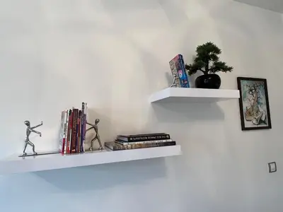 two white shelves on a wall with books at Quiet apartment in the centre in Prague