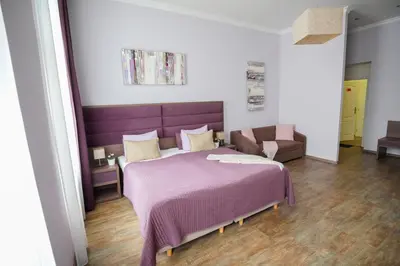 a bedroom with a purple bed and a couch at Elegant & Stylish Center Apartments! in Prague