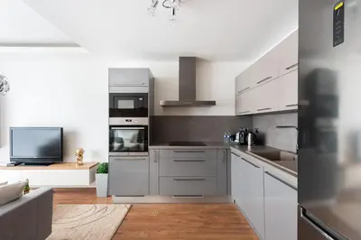 a kitchen with white cabinets and a flat screen tv at Luxury & air-conditioned Osko Apartment near the city center in Prague