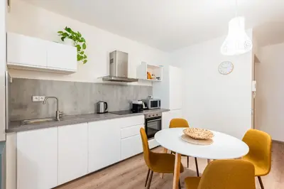 a kitchen with white cabinets and a table and chairs at Diamond River in Prague