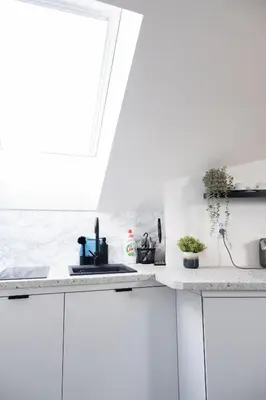a white kitchen with a sink and a window at Rentero Artsy Roof Top Apartment in City Centre in Prague