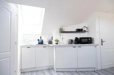 a white kitchen with white cabinets and a window at Rentero Artsy Roof Top Apartment in City Centre in Prague