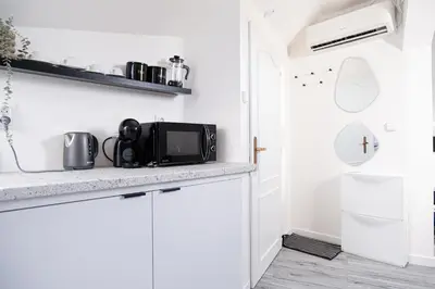 a kitchen with white cabinets and a microwave at Rentero Artsy Roof Top Apartment in City Centre in Prague