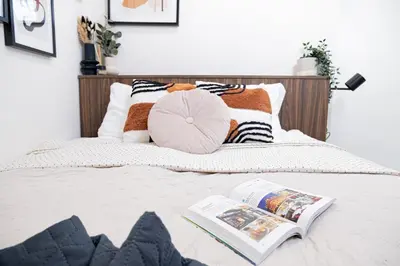 a bed with a heart pillow and a book on it at Rentero Artsy Roof Top Apartment in City Centre in Prague