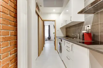 a kitchen with white cabinets and a brick wall at Dream Apartments Prague in Prague