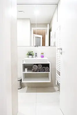 a white bathroom with a sink and a mirror at Rentero Scandinavian - Private Garden APT in Prague