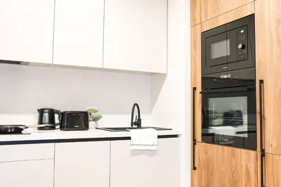 a kitchen with white cabinets and a black microwave at Rentero Michelska Residence Scandinavian Quiet Apartment, Prague in Prague