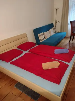 a bedroom with a bed with red sheets and a couch at Comfy home in Vinohrady in Prague