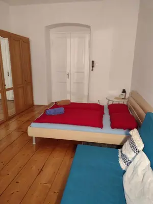 a bedroom with a bed with red sheets and a blue couch at Comfy home in Vinohrady in Prague