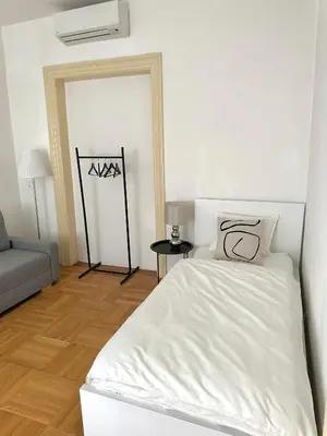 a white bedroom with a bed and a couch at Byt ve městě Praha 2 in Prague