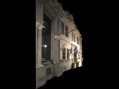 a building with a flag on the side of it at night at Apartmány na Náměstí in Český Brod