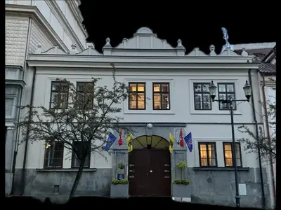 a white building with flags in front of it at Apartmány na Náměstí in Český Brod