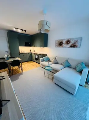 a living room with a white couch and a kitchen at Nika Apartments Prague 5 in Prague