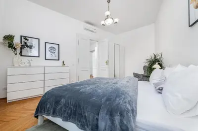 a white hallway with a chair and a cross on the floor at Quiet apartment in the Old Town in Prague