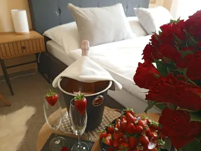 a table with two wine glasses and strawberries on a bed at Penzion Flídr in Poděbrady