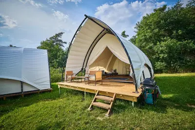 a tent and a wooden table in a field at Glamping Slapy in Slapy