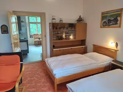 a bedroom with two twin beds and a kitchen at Pension 21 in Prague
