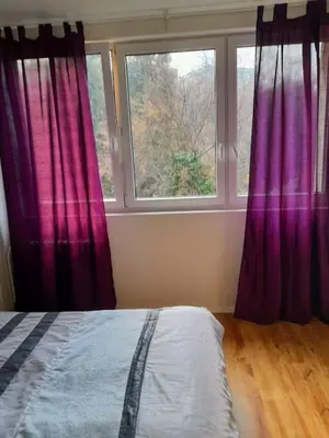 a bedroom with purple curtains and a bed and a window at LEV I SOVA in Mělník