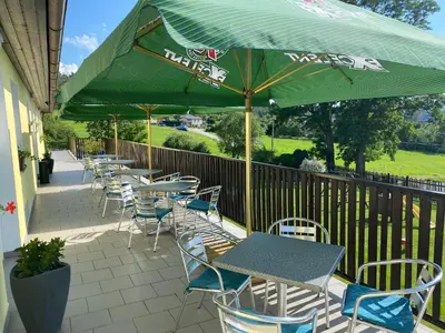 a row of tables and chairs with a green umbrella at Penzion Kamejk in Kamýk nad Vltavou