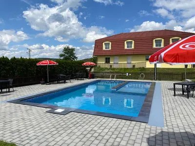 a swimming pool with umbrellas and a house at Penzion Kamejk in Kamýk nad Vltavou