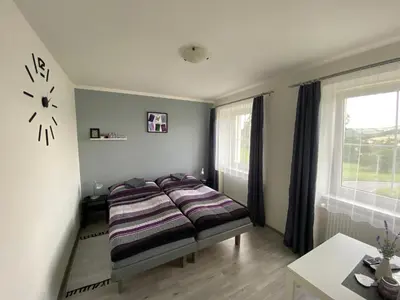 a bedroom with a bed and a clock on the wall at Penzion Kamejk in Kamýk nad Vltavou