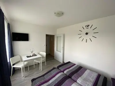 a bedroom with a bed and a clock on the wall at Penzion Kamejk in Kamýk nad Vltavou