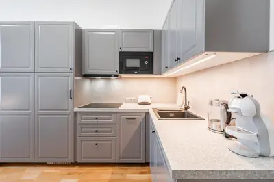 a kitchen with white cabinets and a sink at Charming Apartment in Spain St in Prague