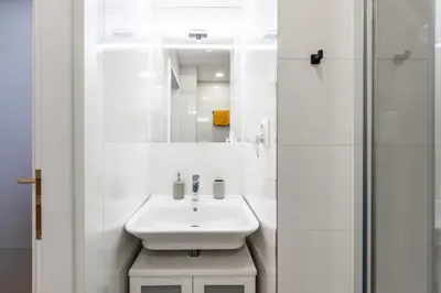 a white bathroom with a sink and a shower at Charming Apartment in Spain St in Prague