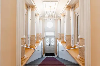 a hallway with stairs in a building with a chandelier at Charming Apartment in Spain St in Prague