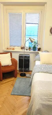a bedroom with a bed and a couch and two windows at Warm room in the beautiful Smíchov - Prague in Prague