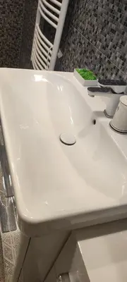 a white bathroom sink with a green sponge on it at Warm room in the beautiful Smíchov - Prague in Prague