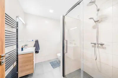 a bathroom with a glass shower and a sink at Dům u Prokopského údolí in Prague
