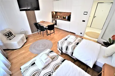 a room with two beds and a table and a kitchen at Jasminn Apartments in Prague